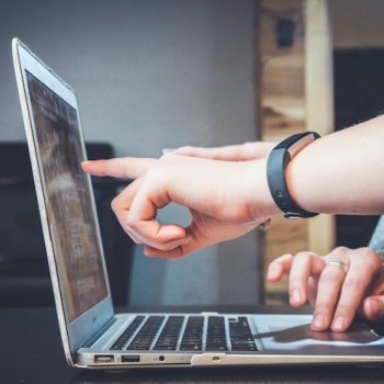 hand pointing to a laptop screen