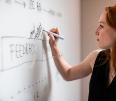 woman writing a marketing strategy on a whiteboard