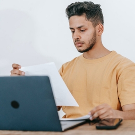 man reading a document in front of his laptop